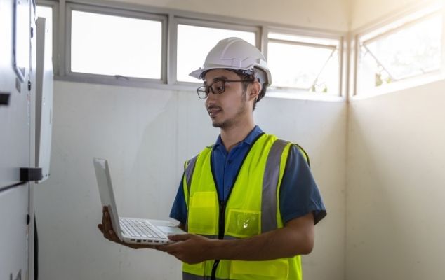 Engineer ICI Automation melakukan audit efisiensi energi dan monitoring parameter Inverter VFD industri menggunakan laptop