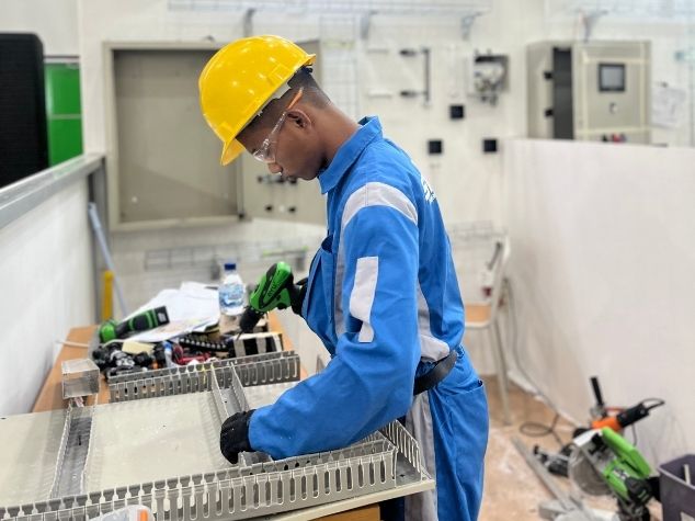 Teknisi muda berbakat jebolan kompetisi elit LKS Nasional sedang merakit instalasi panel kontrol otomasi industri.