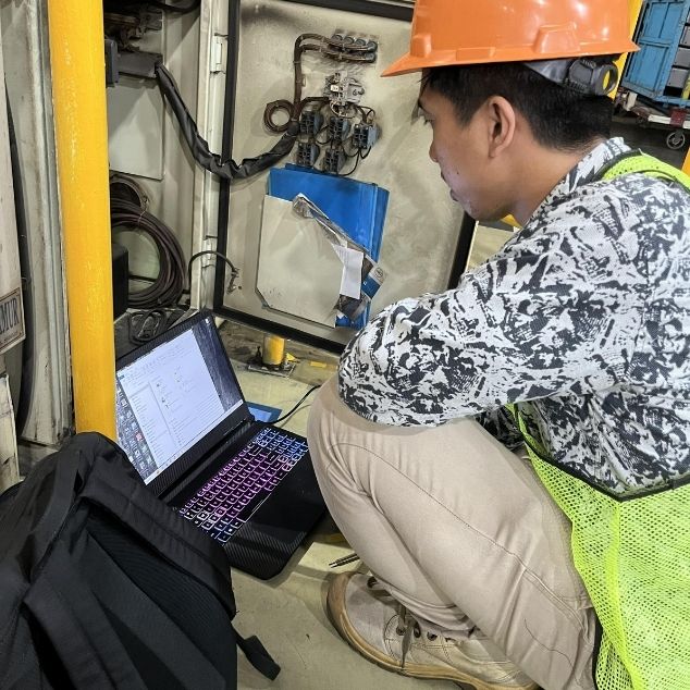 Engineer ICI Automation dengan APD lengkap melakukan integrasi jaringan panel mesin produksi untuk update database di pabrik TMMIN Karawang.